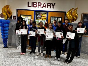 Young teen students stand in a school hallway with certificates