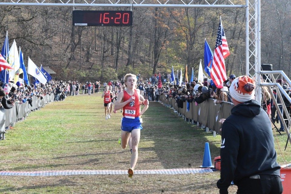 A high school runner goes across the finish line at an outdoor race.