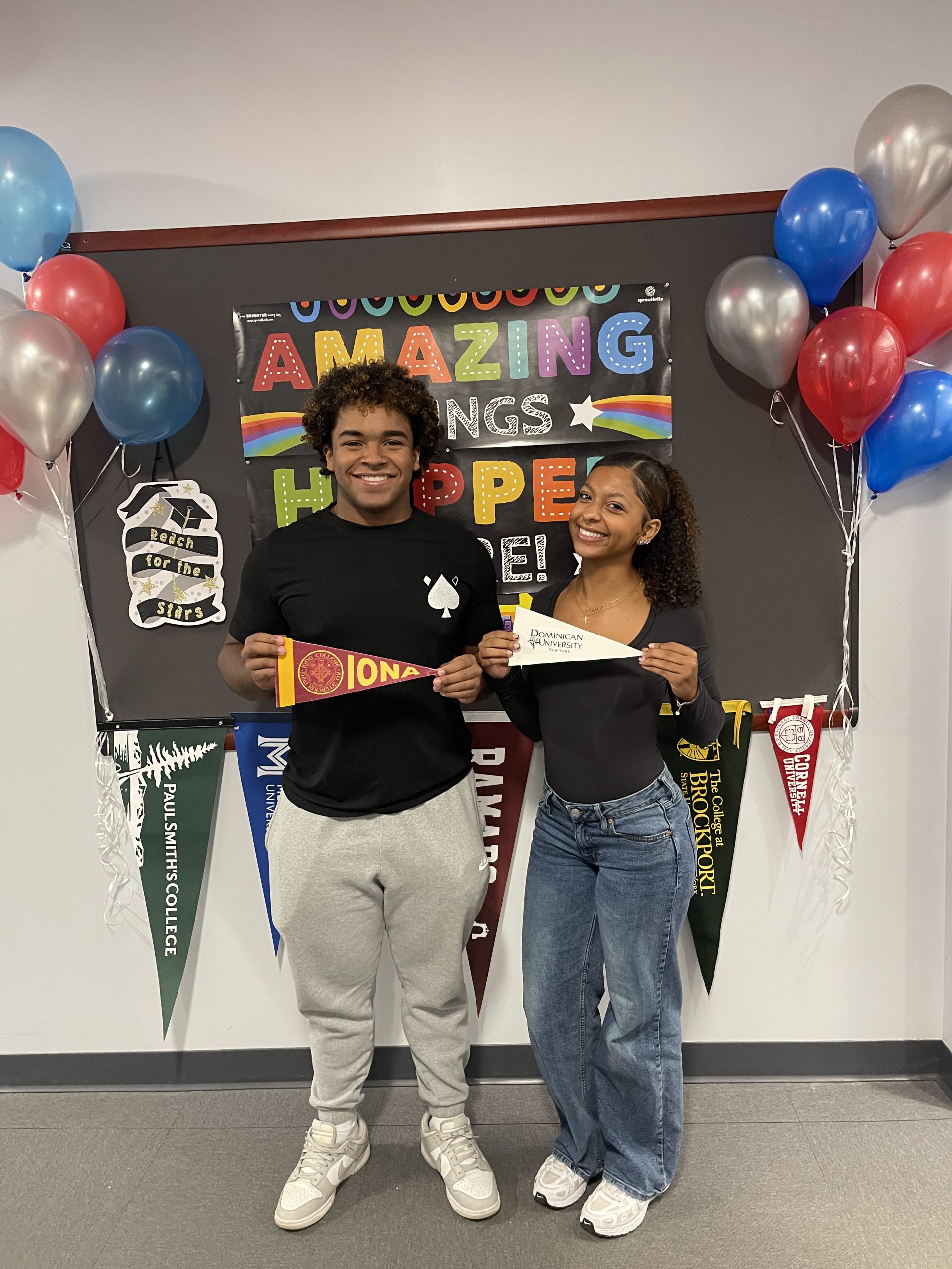 Students smiling in front of a bulletin board that says Amazing Things Happen Here