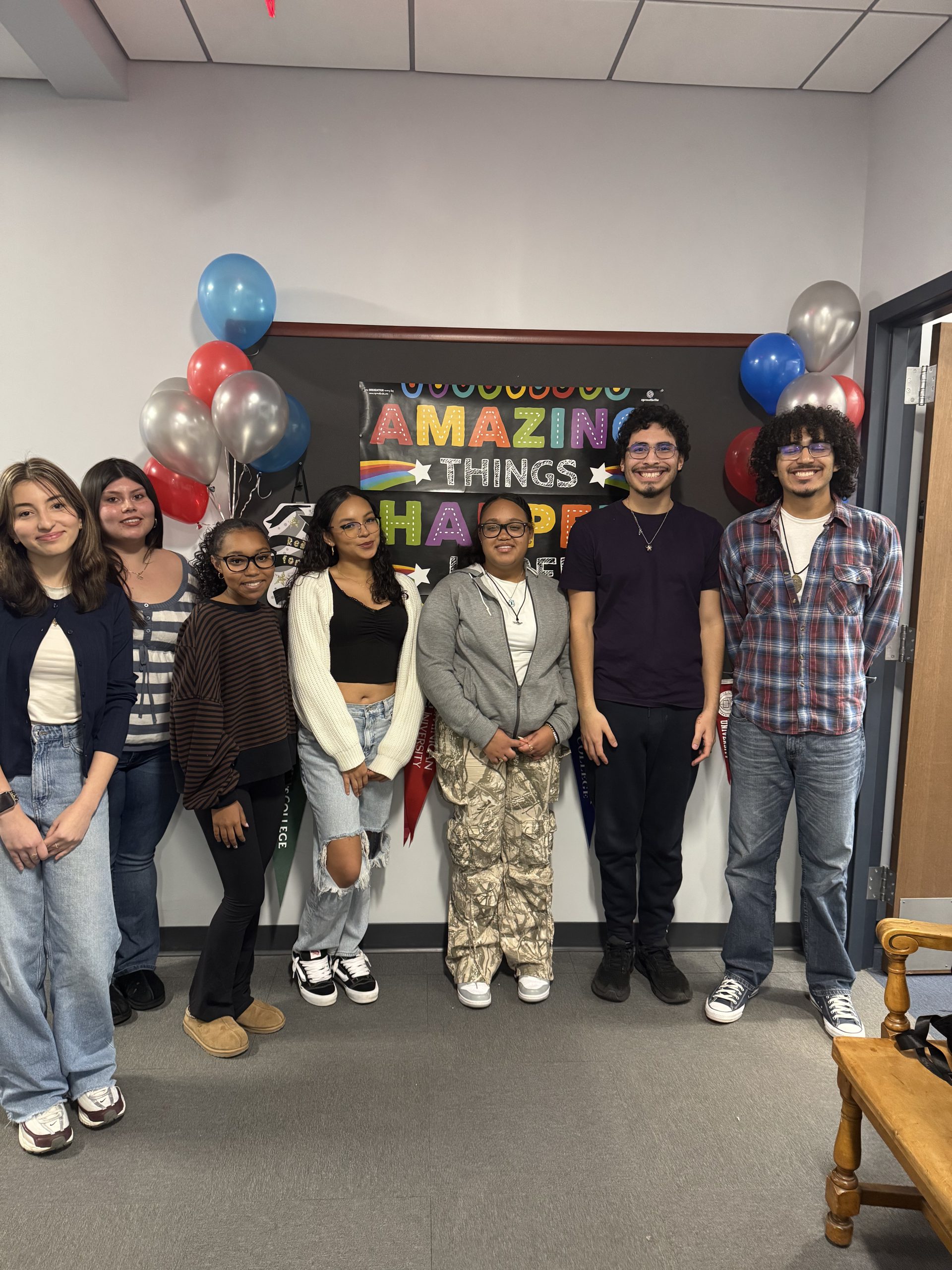 Group of students in front of bulletin board that says Amazing Things Happen Here