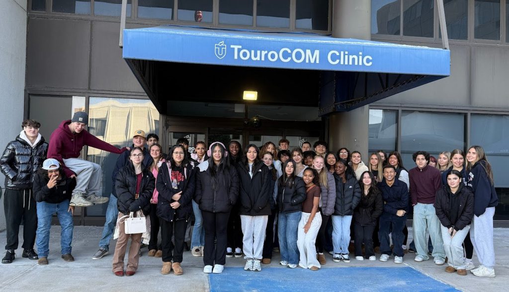 High school students stand outside a building with a blue canopy that says TouroCOM Clinic