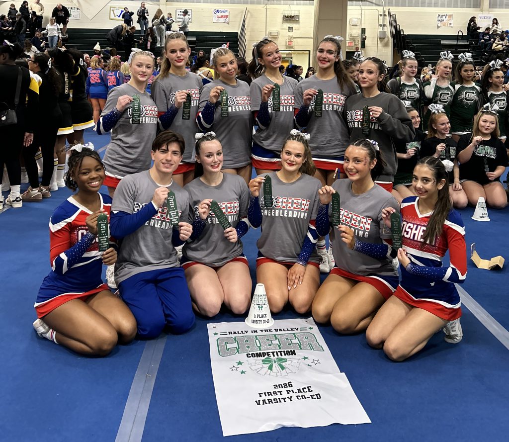 Cheerleading team poses in a gym with medals