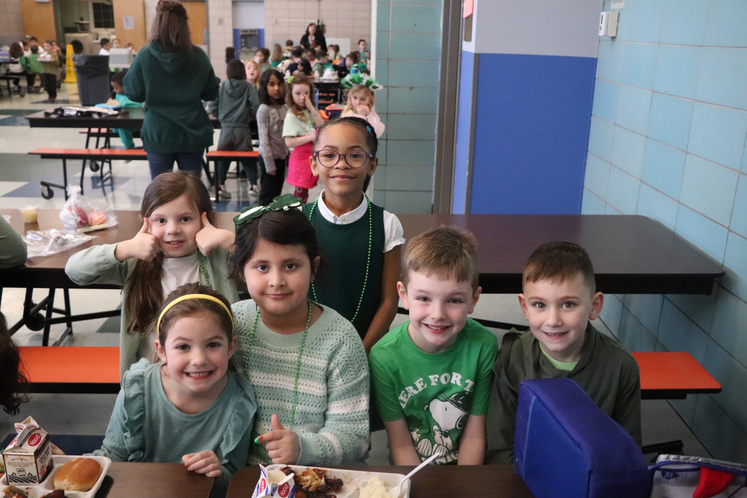 Three students hold hands and walk into school together on the first day of school.