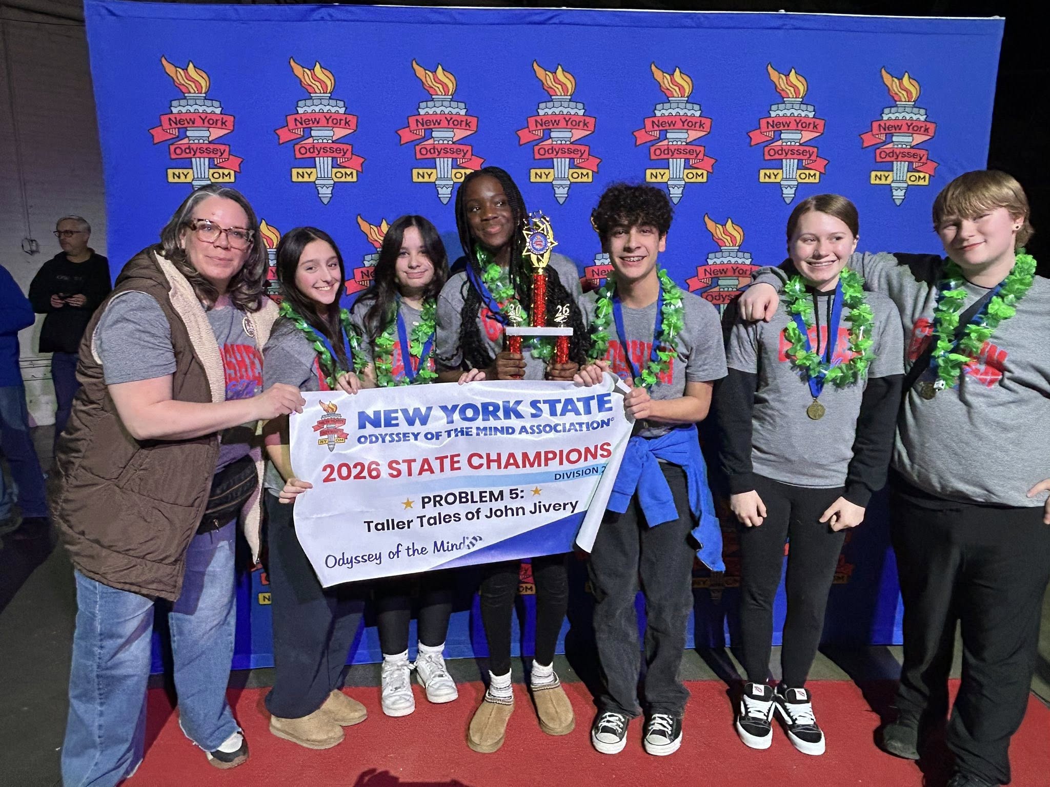 Art Teacher sits at an art easel at a lake with two students standing next to her.