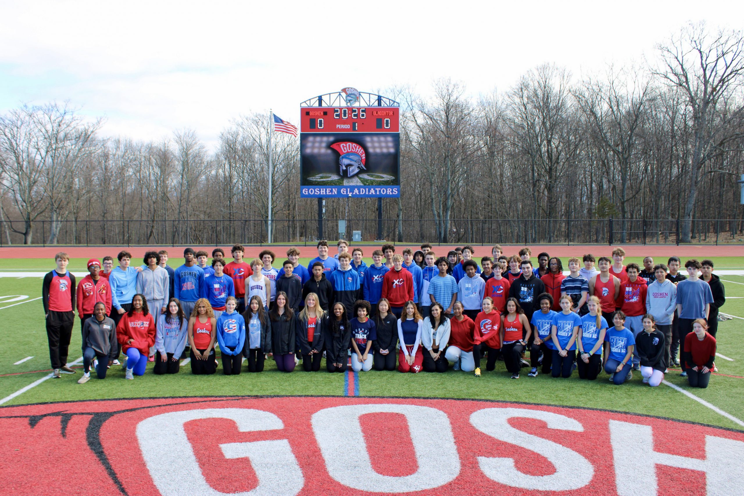 Goshen's Varsity Winter Track team. Everyone is standing together on the football field with the Goshen logo below them. 
